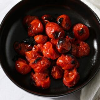 A black bowl of roasted tomatoes