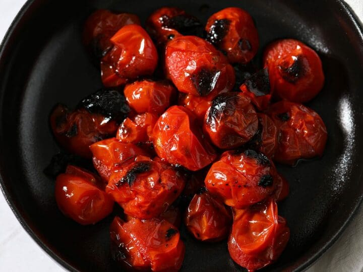 A black bowl of roasted tomatoes