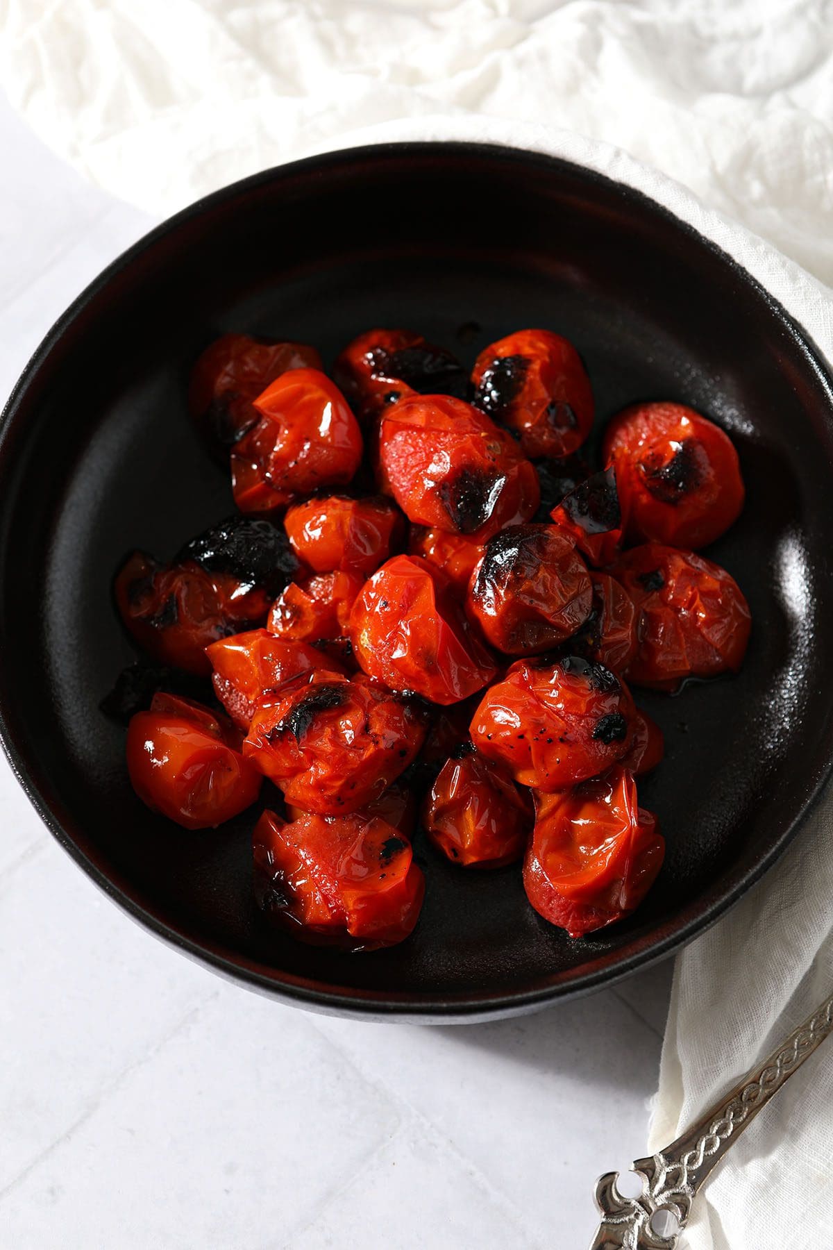 A black bowl of roasted tomatoes