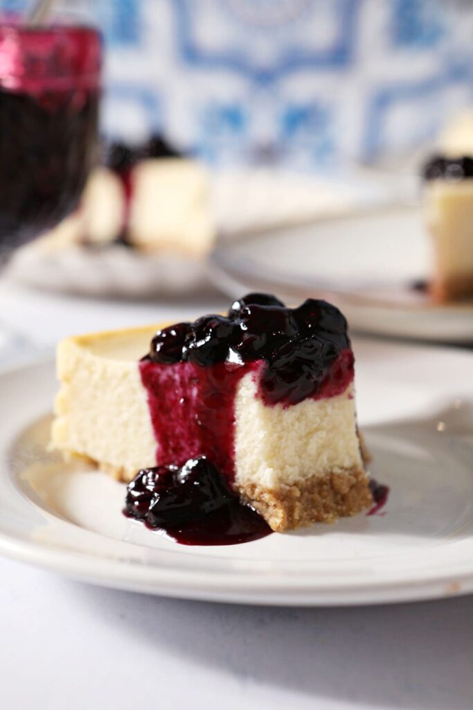 Close up of a slice of cheesecake topped with blueberry sauce