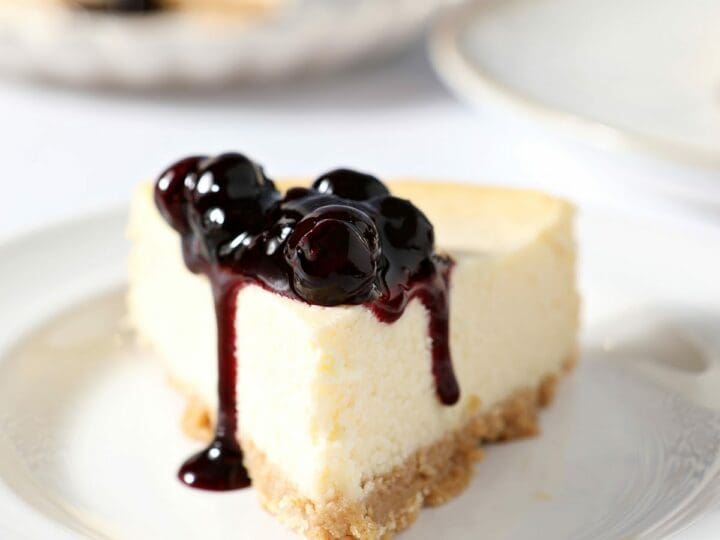 A slice of cheesecake topped with blueberry sauce