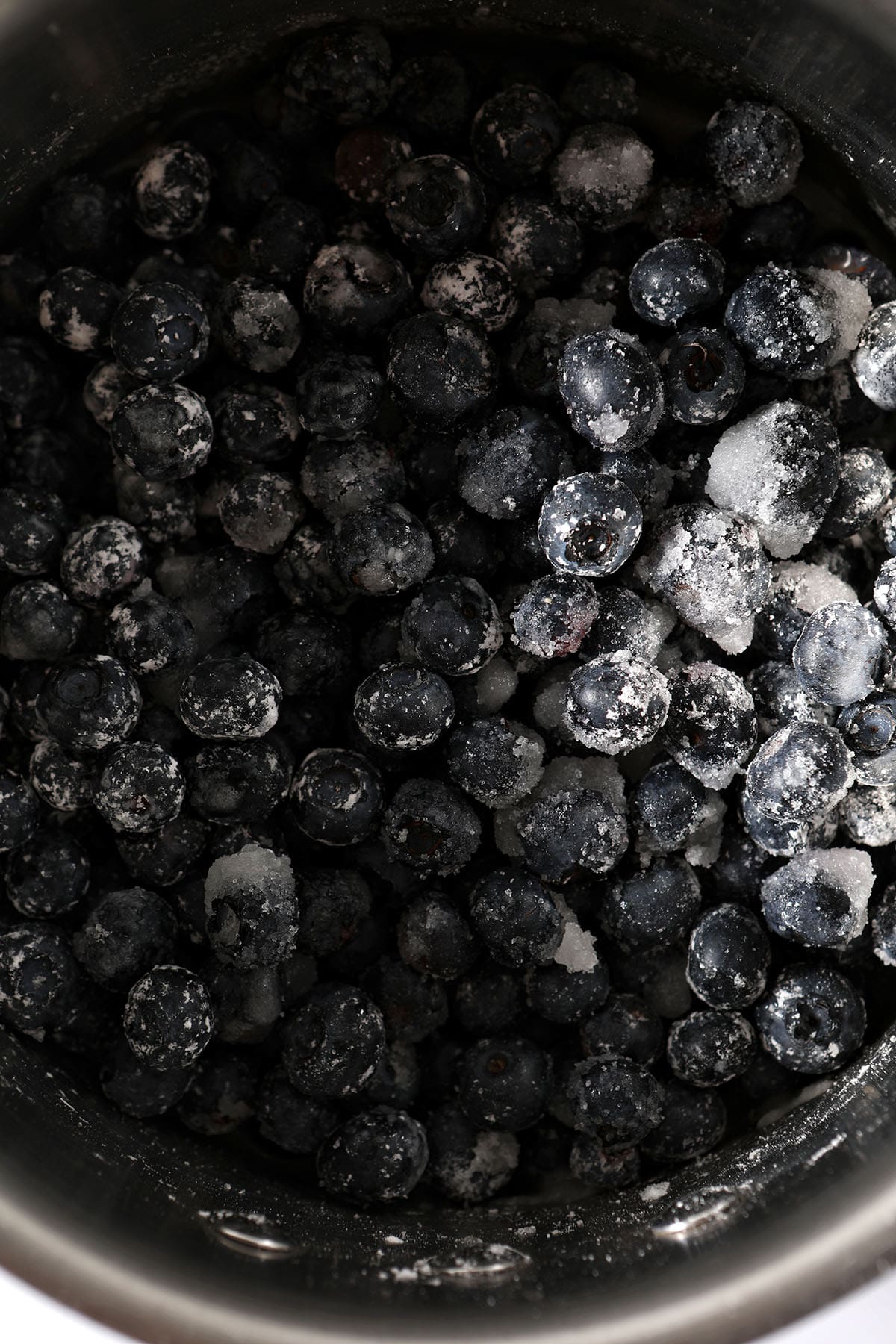close up of blueberries tossed in ingredients in a saucepan to make a sauce