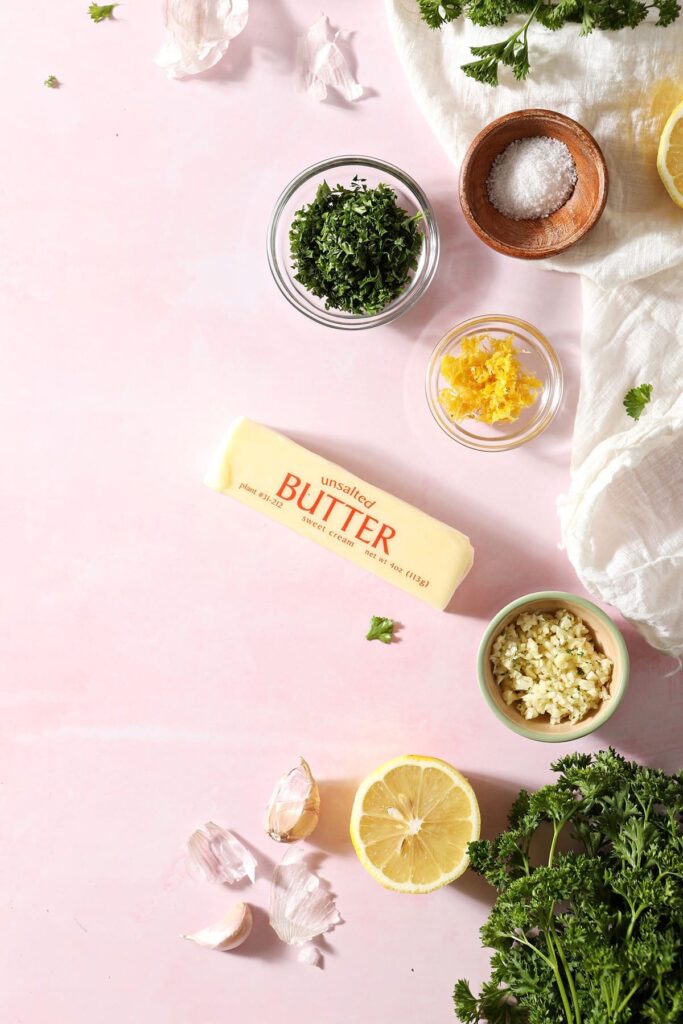 Ingredients for compound butter and the rest of the ingredients in bowls on a pink background