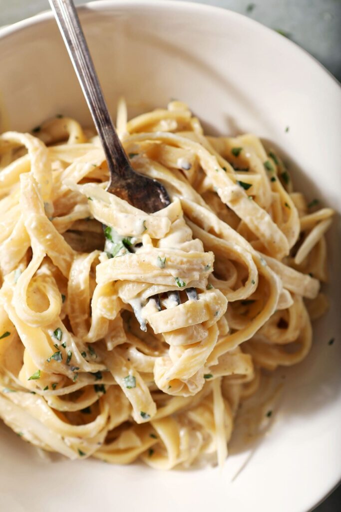 A fork twirled in thin pasta noodles in a cream sauce