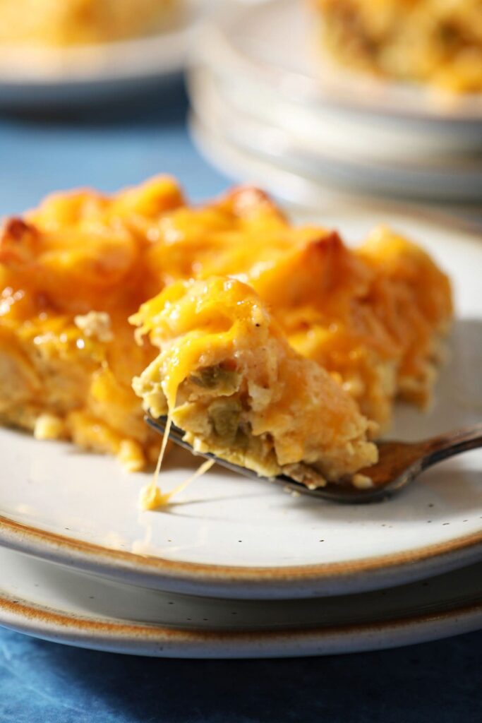 A fork holds a bite of an egg casserole on a plate