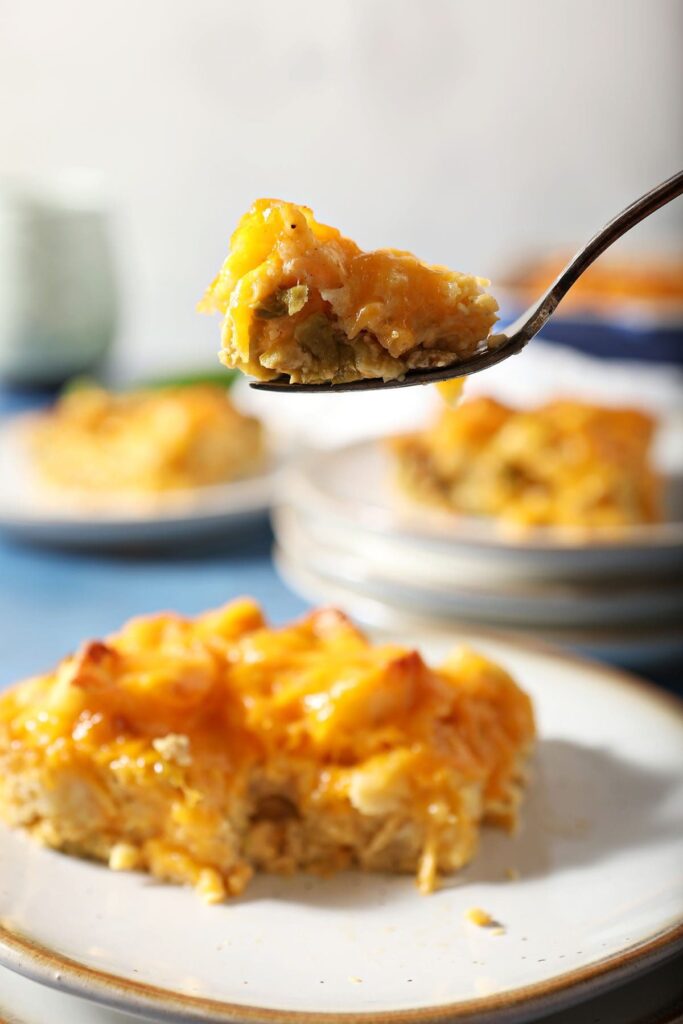 A fork lifts a bite of Hatch Chile egg casserole above a plate