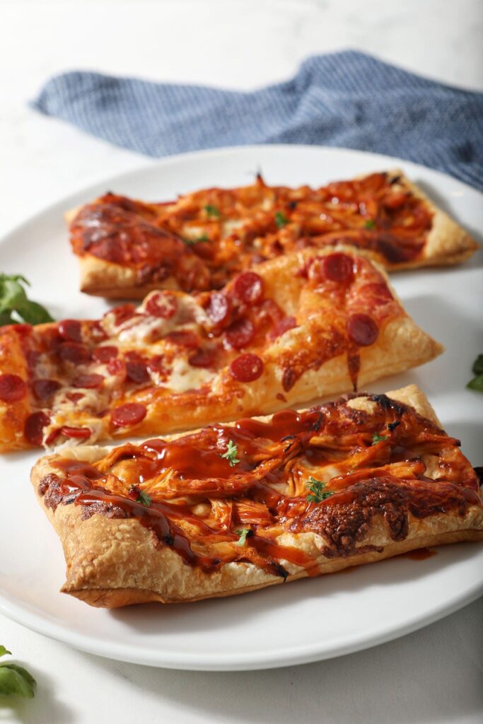 Three individual puff pastry pizzas on a white serving tray