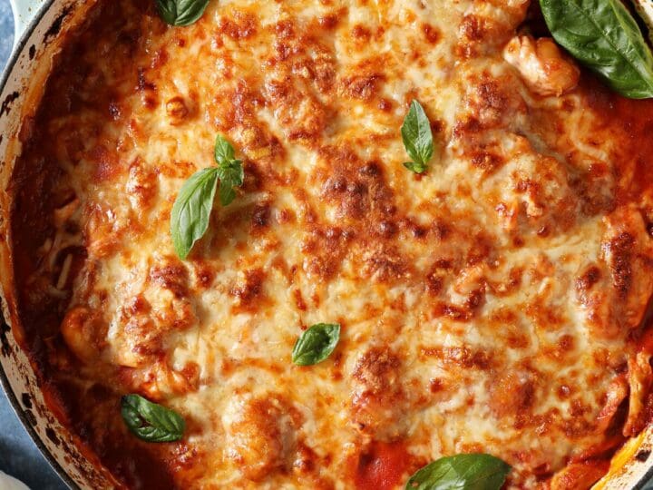 Baked Gnocchi with Chicken in a baking dish on a blue table garnished with fresh basil before serving