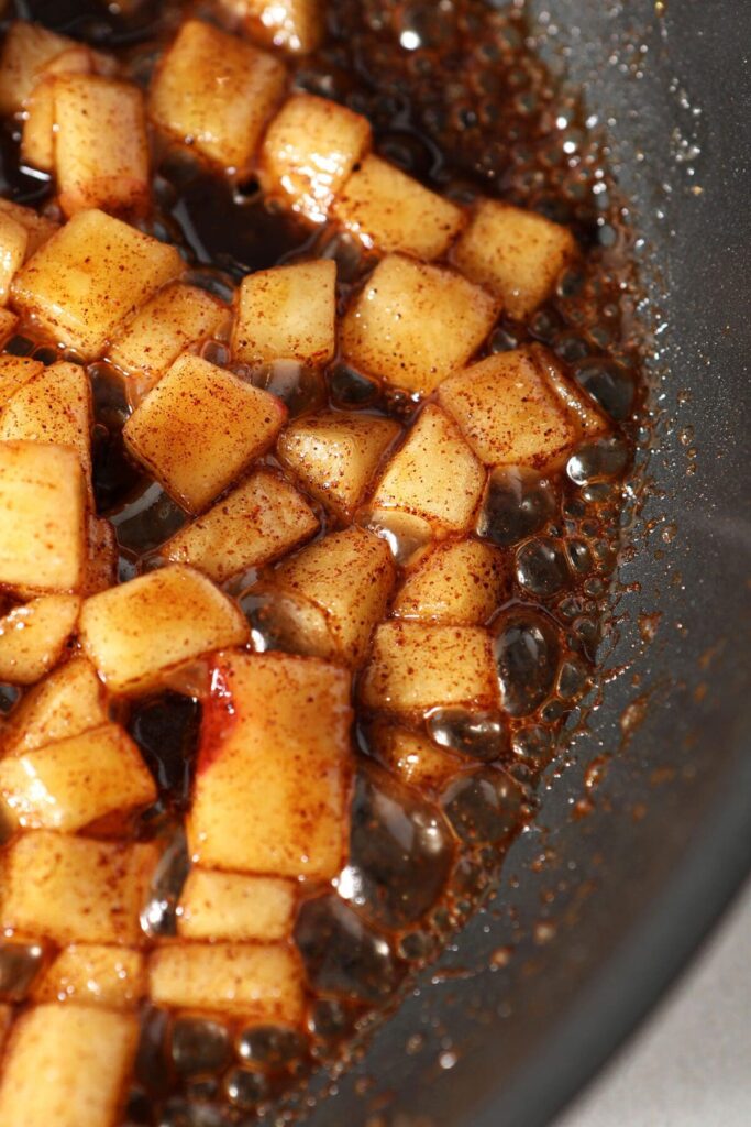 Caramelized apples bubble in a pan while cooking