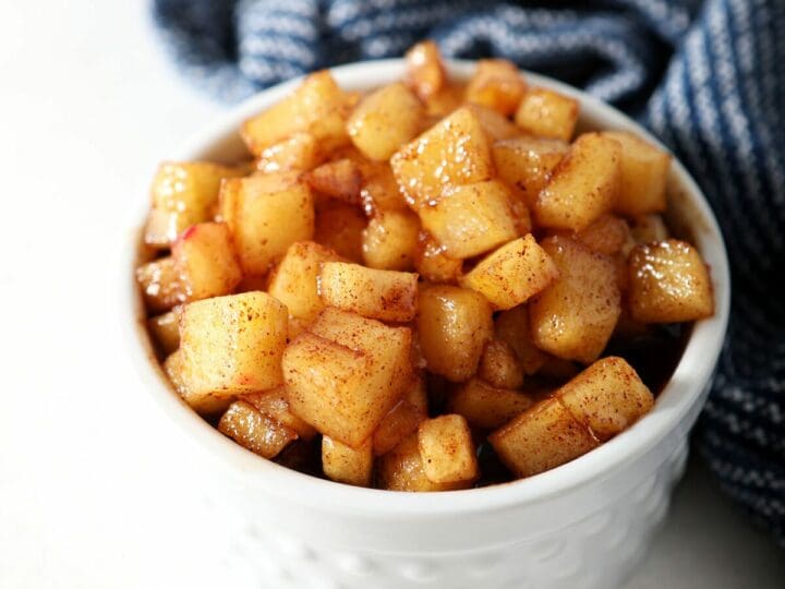 A ramekin of caramelized apples next to a blue striped towel