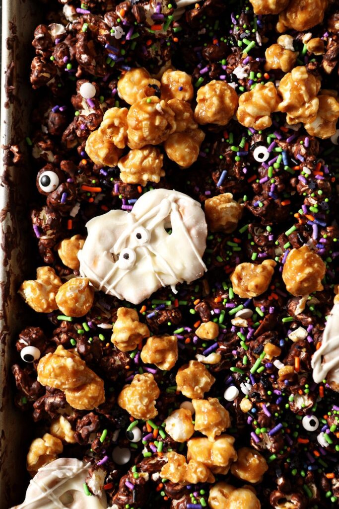 Sweet and salty halloween popcorn snack mix on a sheet pan while cooling