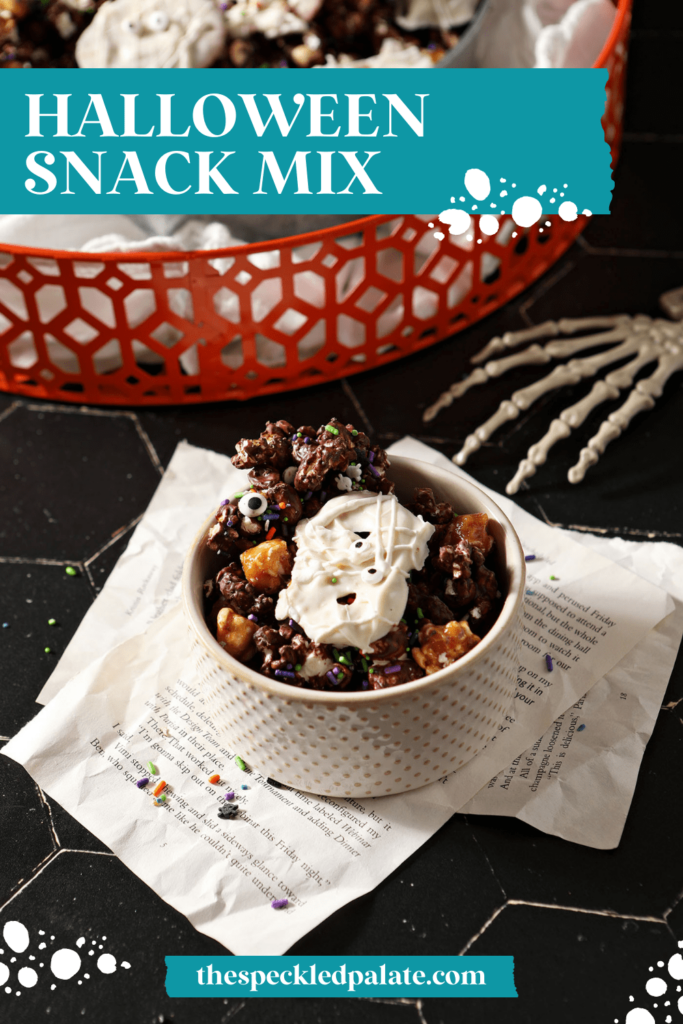 A white bowl of festive chocolate and caramel popcorn with white chocolate covered pretzels with the text halloween snack mix