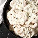Close up of Halloween pretzels in a black bowl decorated like mummies