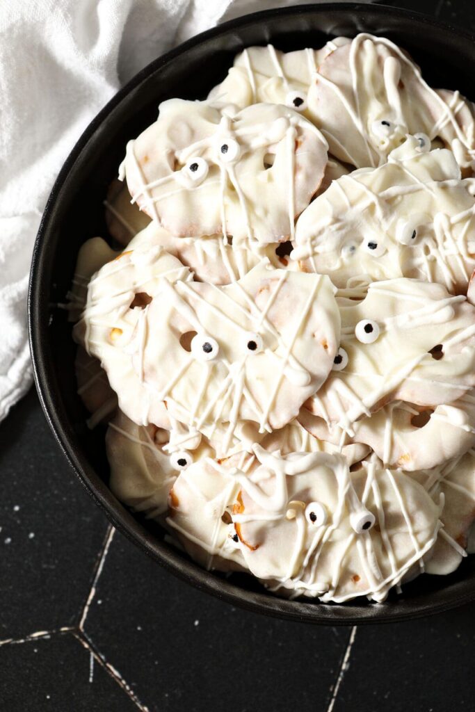 Close up of Halloween pretzels in a black bowl decorated like mummies