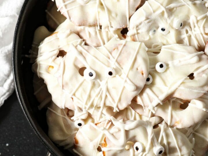 Close up of Halloween pretzels in a black bowl decorated like mummies