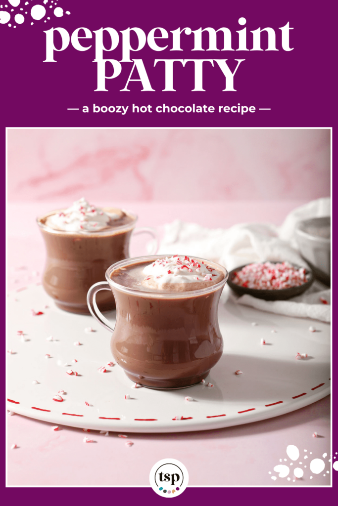 Two mugs of spiked hot cocoa on a white tray garnished with whipped cream and peppermint with the text peppermint patty a boozy hot chocolate recipe