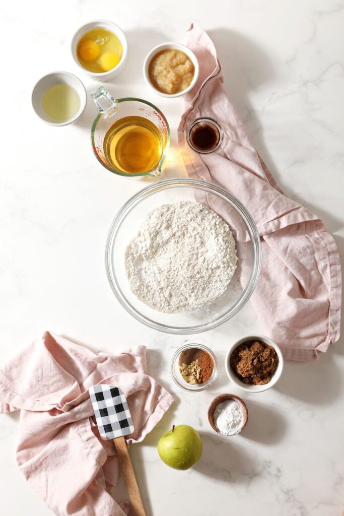 Ingredients to make Apple Pancakes in bowls on marble with pink towels