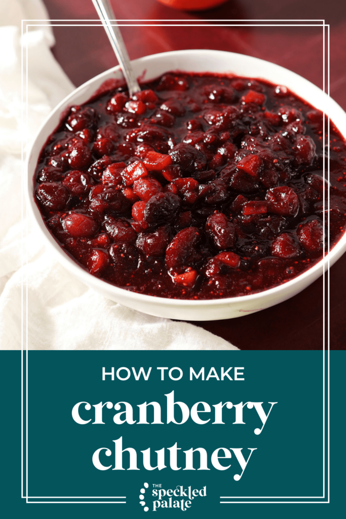 A white bowl of chutney with a spoon in it on a red countertop with a white towel with the text How to Make Cranberry Chutney