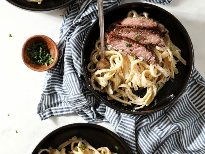 Three bowls of pasta in a cream sauce with steak from above