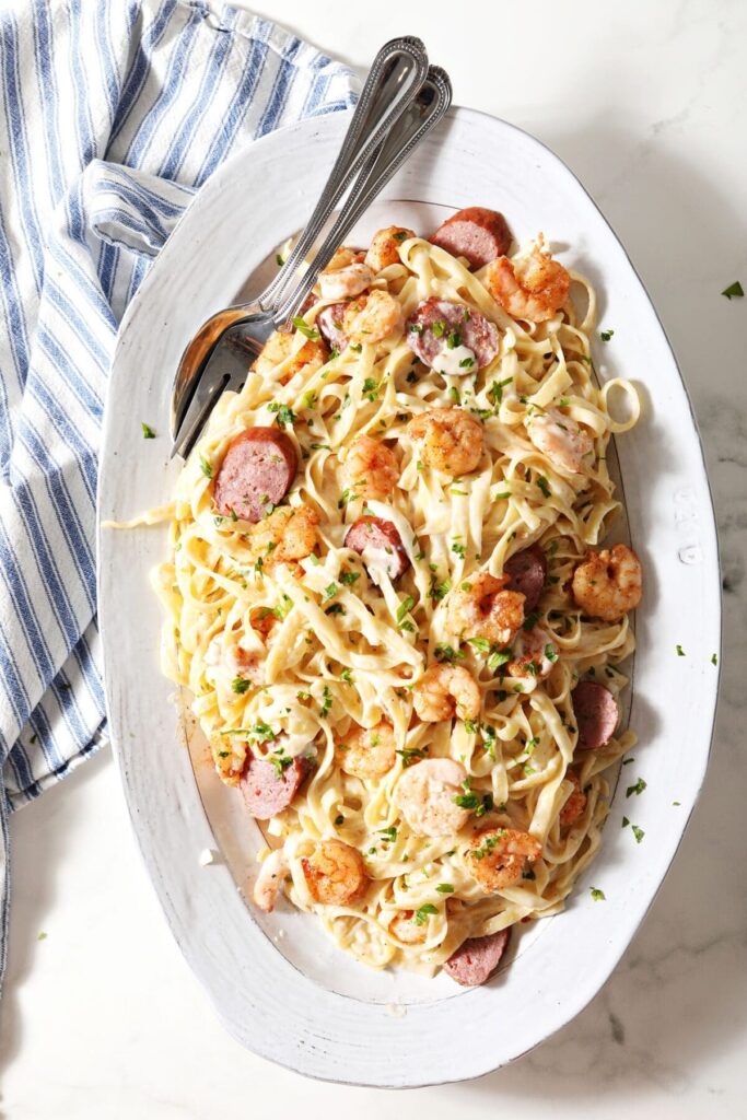 A oblong plate holds an entire recipe of Cajun Shrimp Alfredo on marble