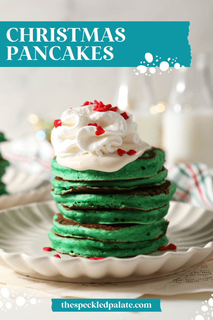 A tower of green pancakes topped with whipped cream and a cream cheese frosting drizzle with heart sprinkles with the text Christmas Pancakes