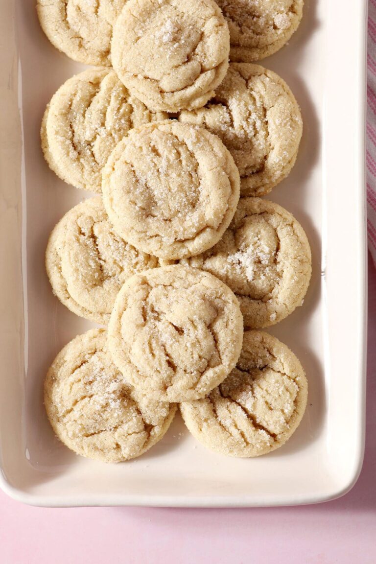 A rectangular platter stacked high with Drop Sugar Cookies on a pink countertop