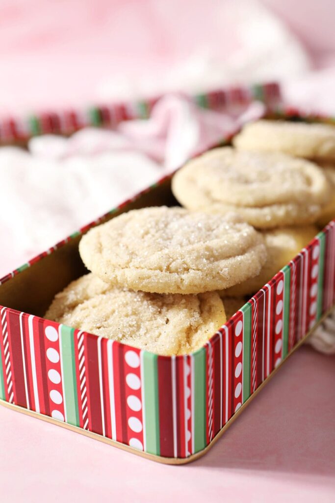 A red and green striped rectangular cookie tin full of drop sugar cookies