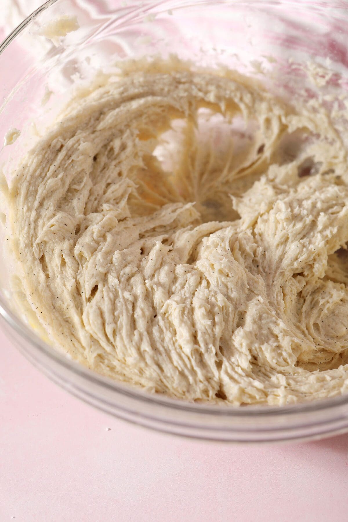 The wet ingredients for the sugar cookies whipped in a bowl on a pink countertop