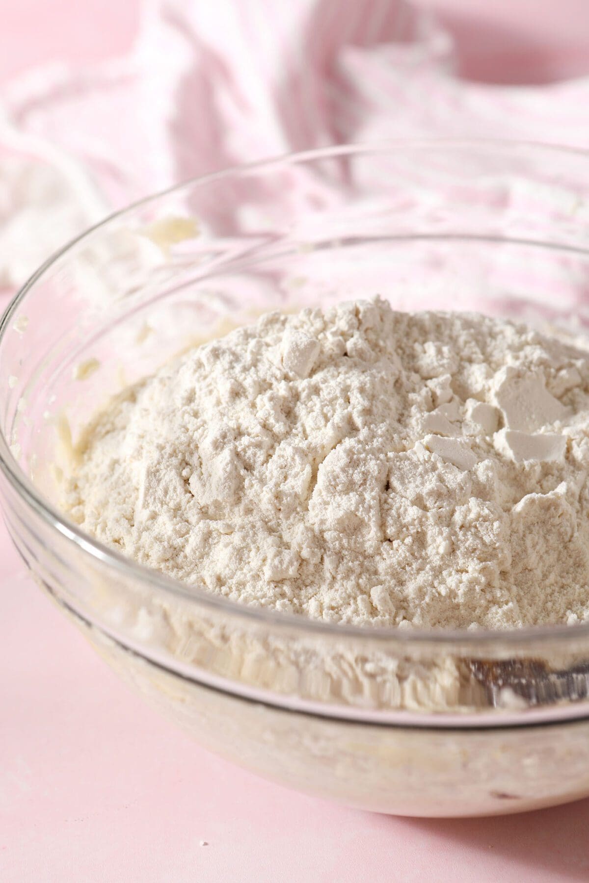 Dry ingredients on top of wet ingredients in a bowl on a pink countertop