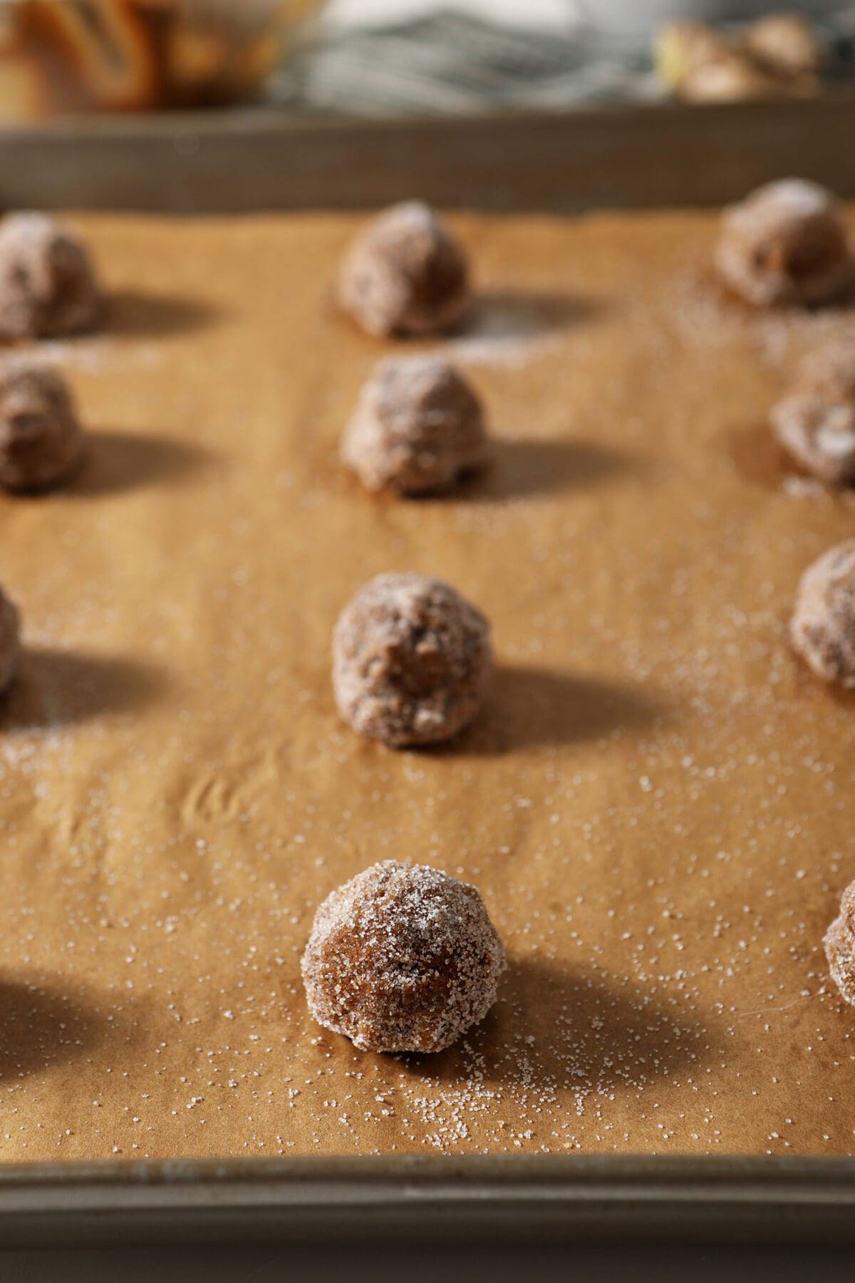 Sugar-coated gingersnap dough balls on a baking sheet before baking