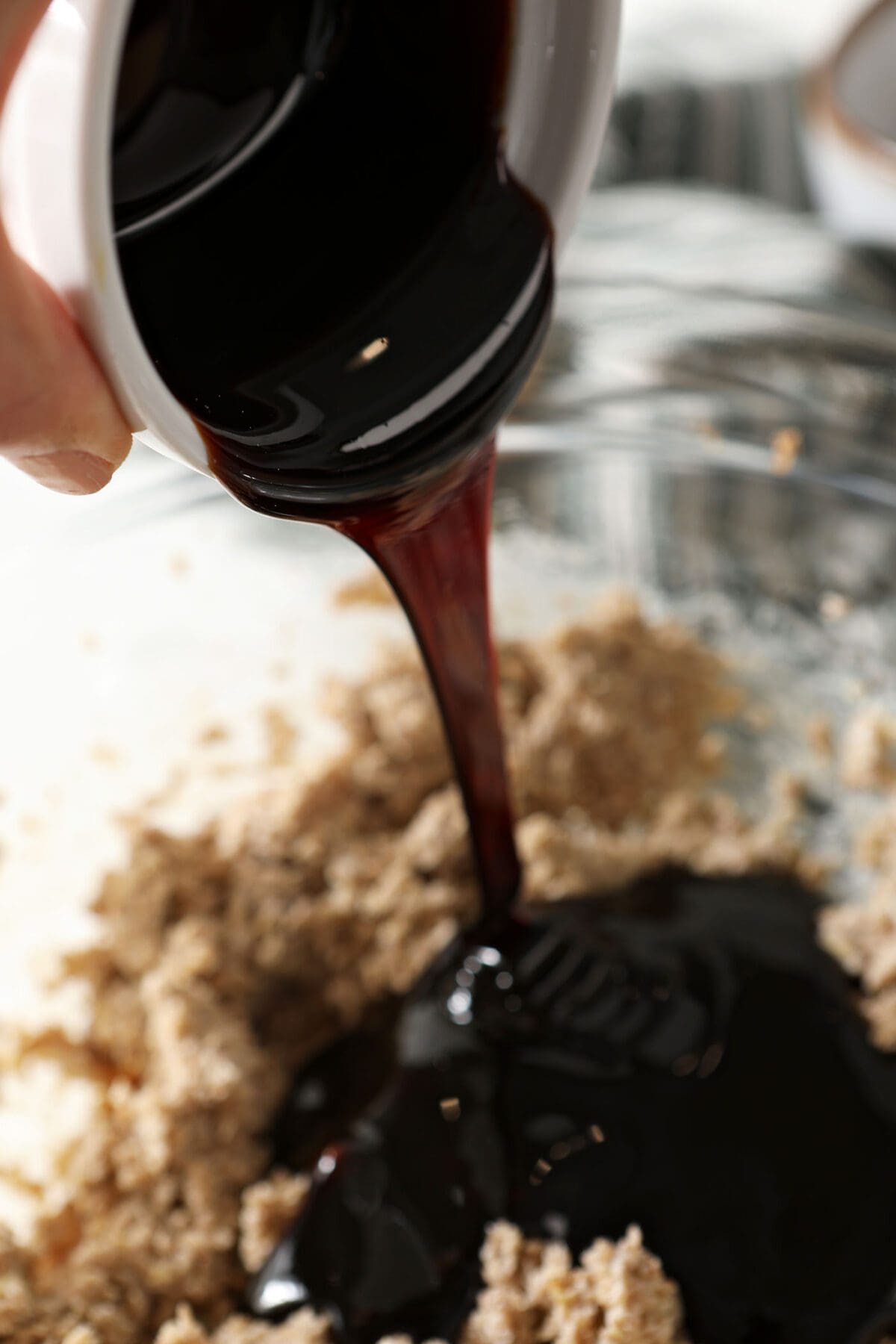 Molasses pours on top of creamed butter mixture in a bowl