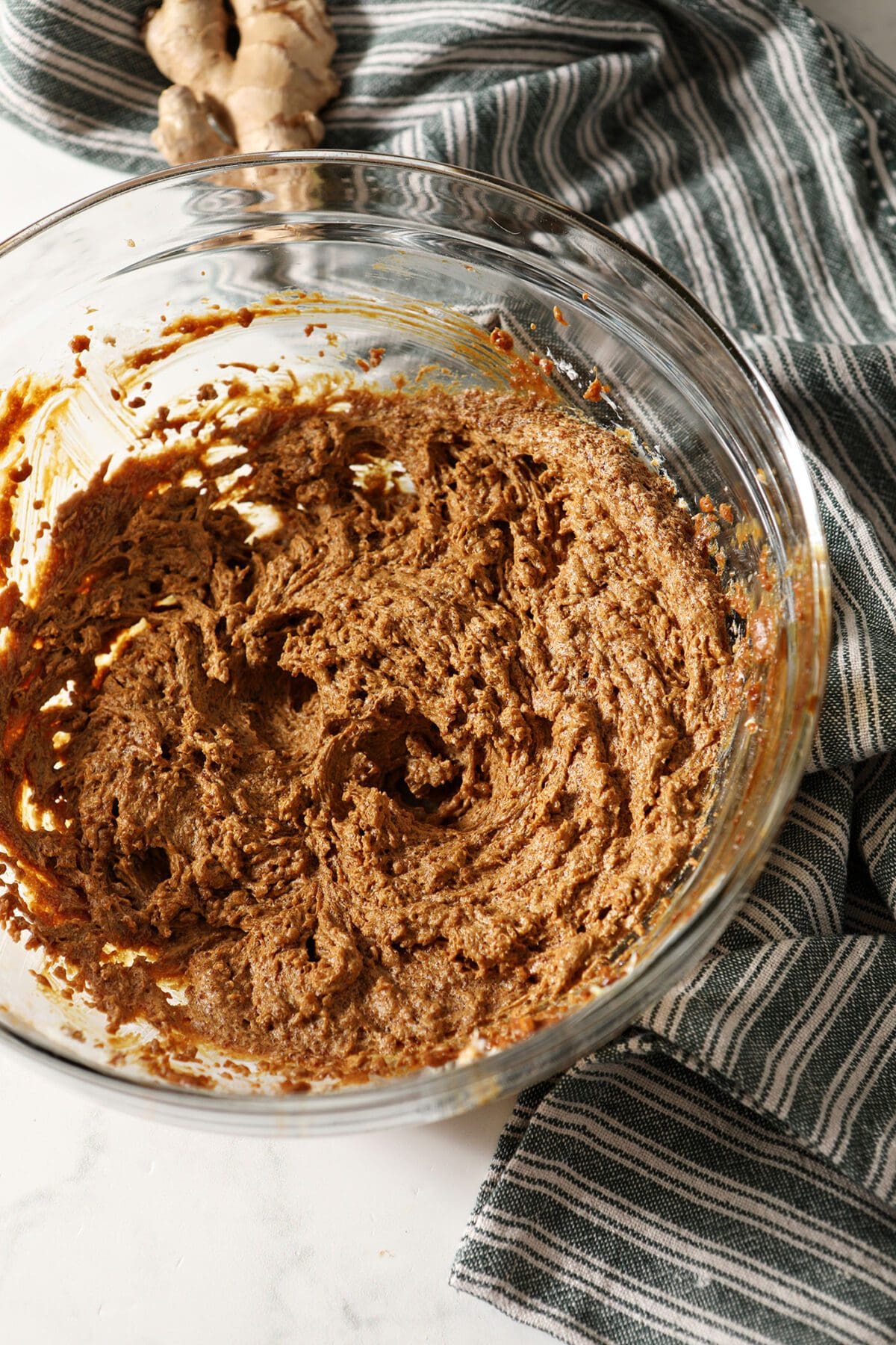 Butter, sugar, ginger and molasses whipped together in a bowl on marble