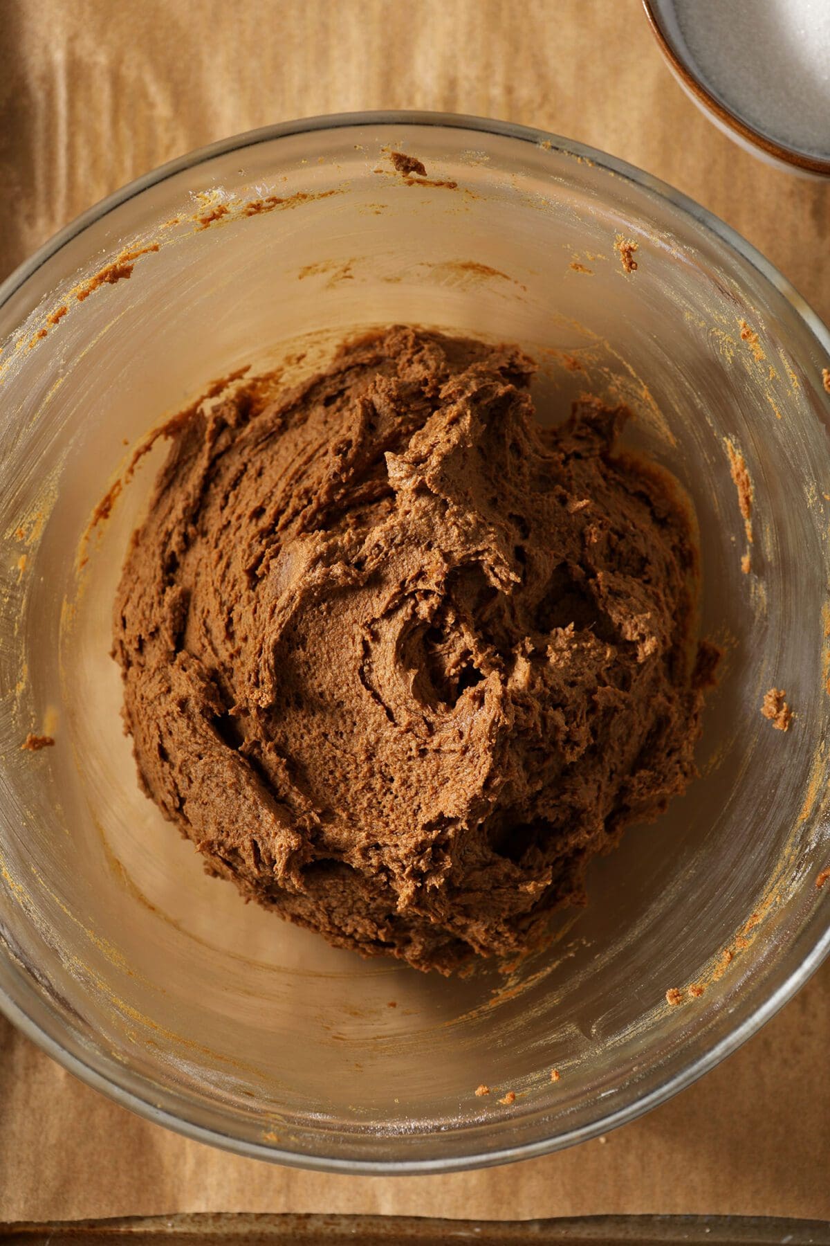 Chilled gingersnap dough in a bowl on top of a parchment-lined sheet pan