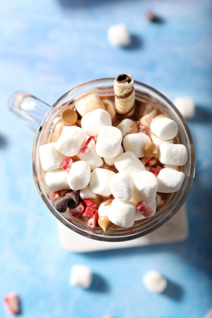 Close up of marshmallows, sprinkles, chocolate chips and more on top of a mug of cocoa