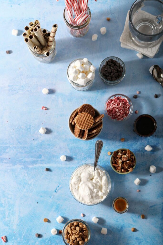 Ingredients in bowls to make a hot chocolate charcuterie board on a blue countertop