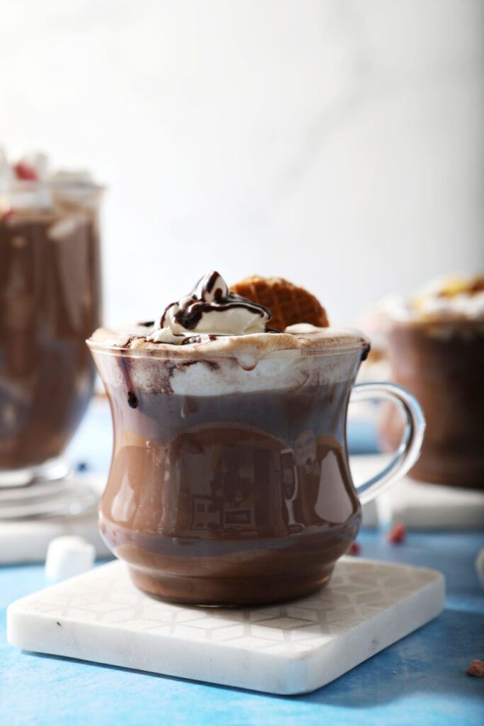 Close up of hot chocolate topped with various toppings next to a hot cocoa board