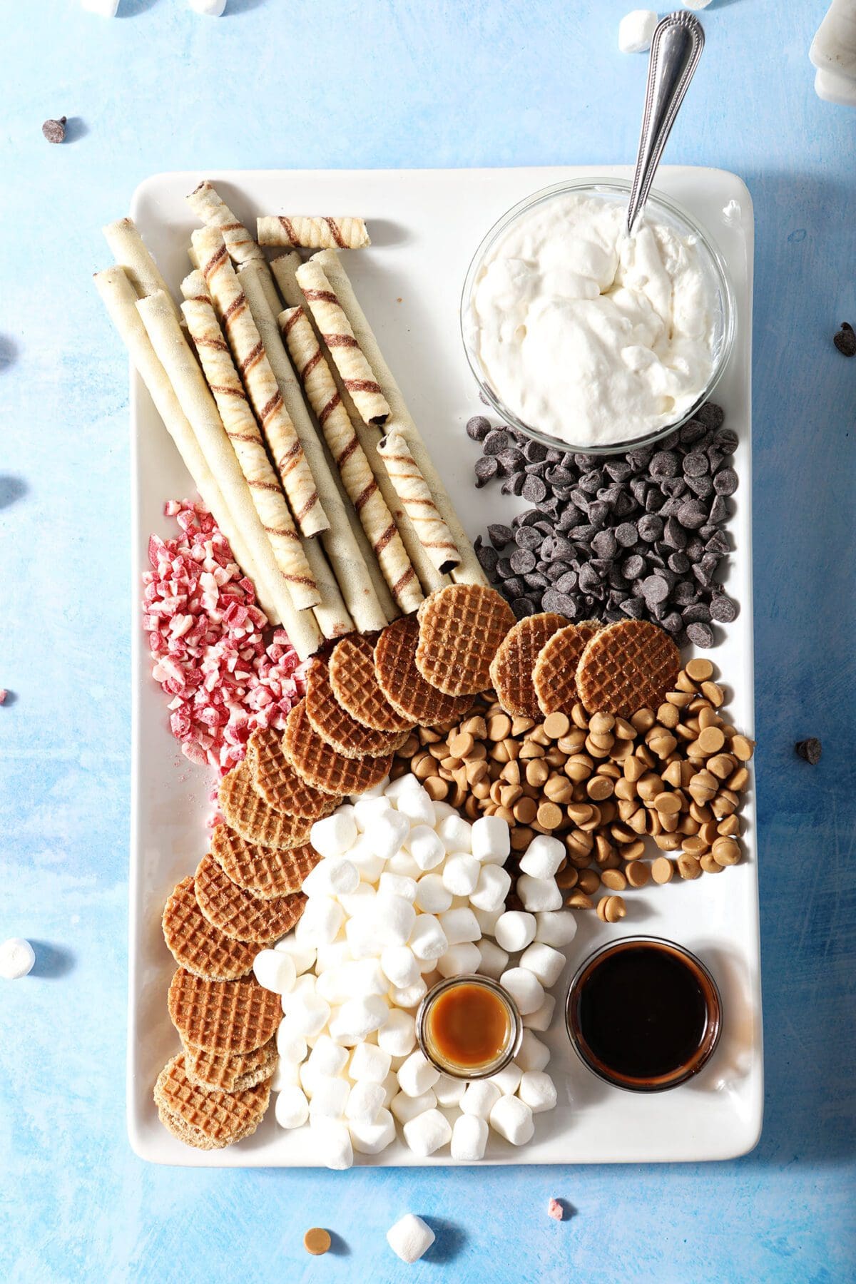 Rolled chocolate cookies with other hot chocolate toppings on a platter