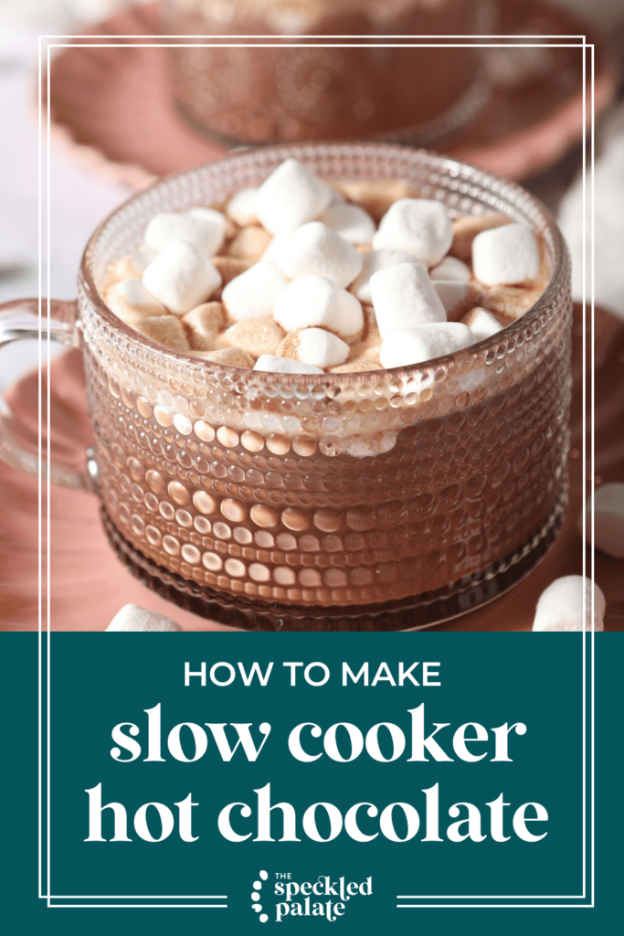 Close up of a glass mug of hot cocoa topped with mini marshmallows on a pink plate with the text How to make Slow Cooker Hot Chocolate