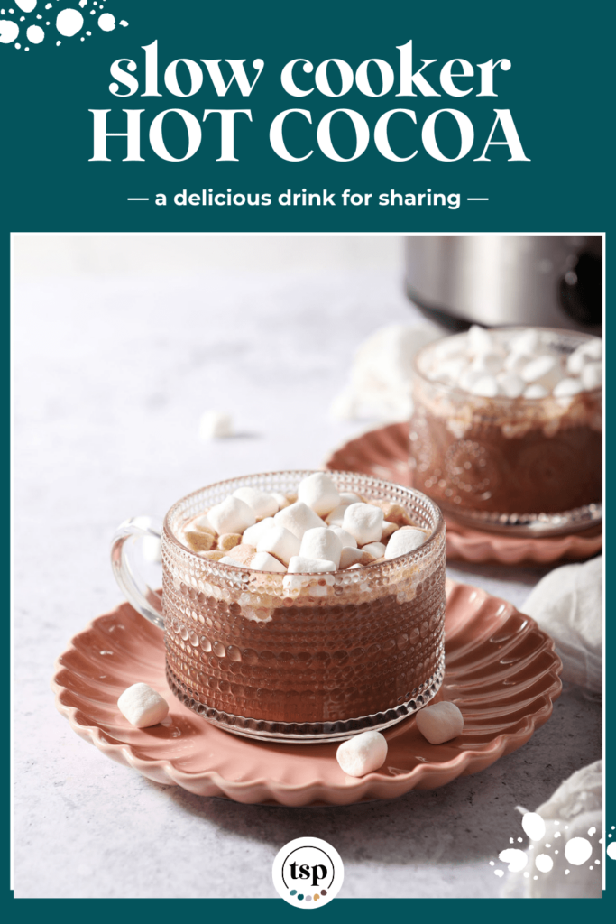 Two glass mugs of hot cocoa topped with marshmallows on pink plates with the text Slow Cooker Hot Cocoa a delicious drink for sharing