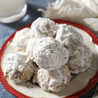 A plate of snowball cookies on a blue countertop