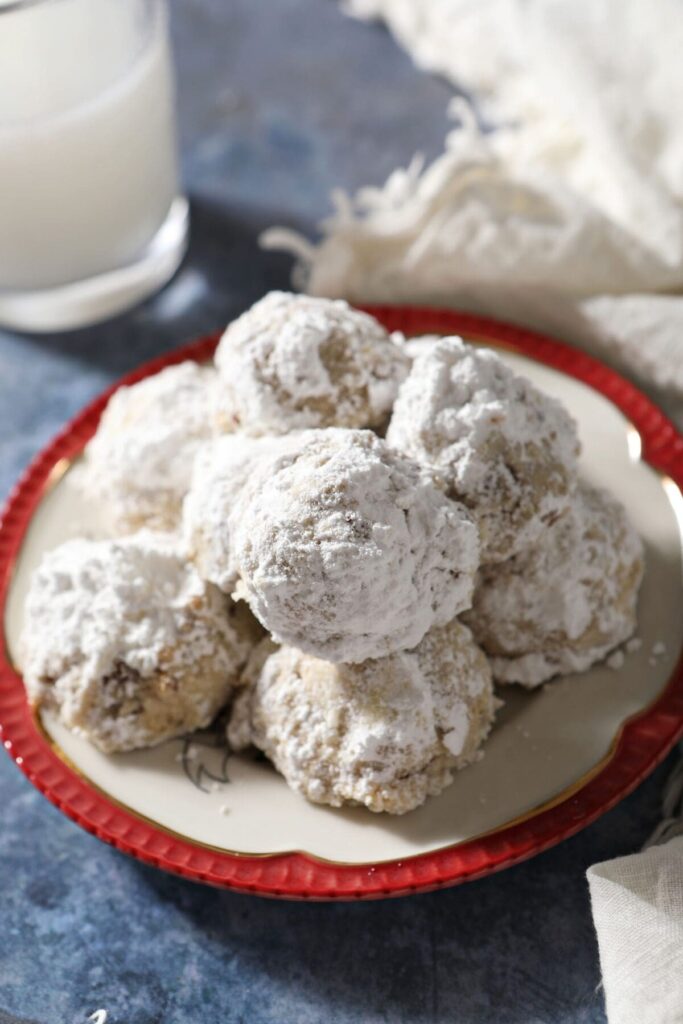 A plate of snowball cookies on a blue countertop