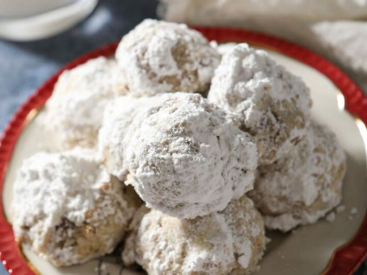 A plate of snowball cookies on a blue countertop