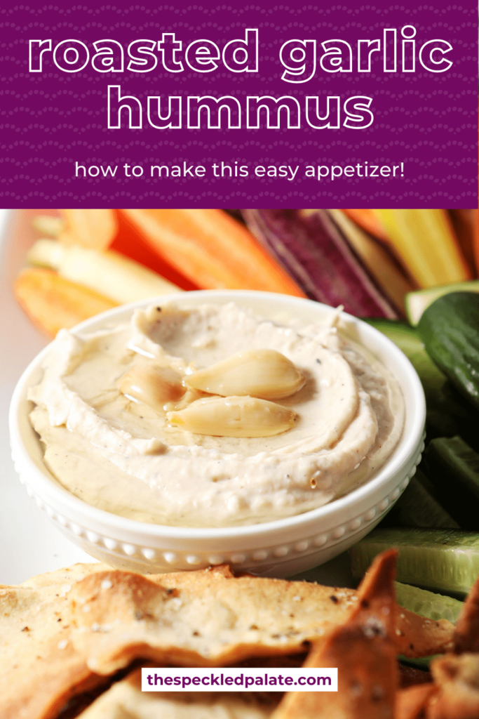 A serving bowl of hummus surrounded by homemade pita chips, cucumbers and carrots with the text Roasted Garlic Hummus how to make this easy appetizer