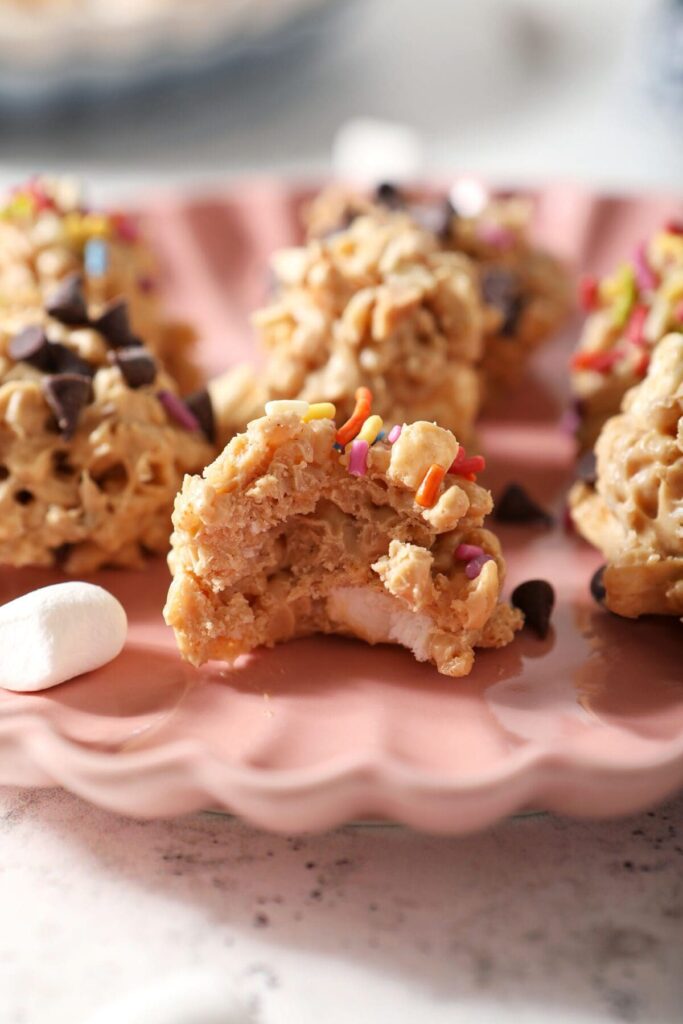 Close up of a bitten-into Avalanche Cookie topped with sprinkles on a pink plate