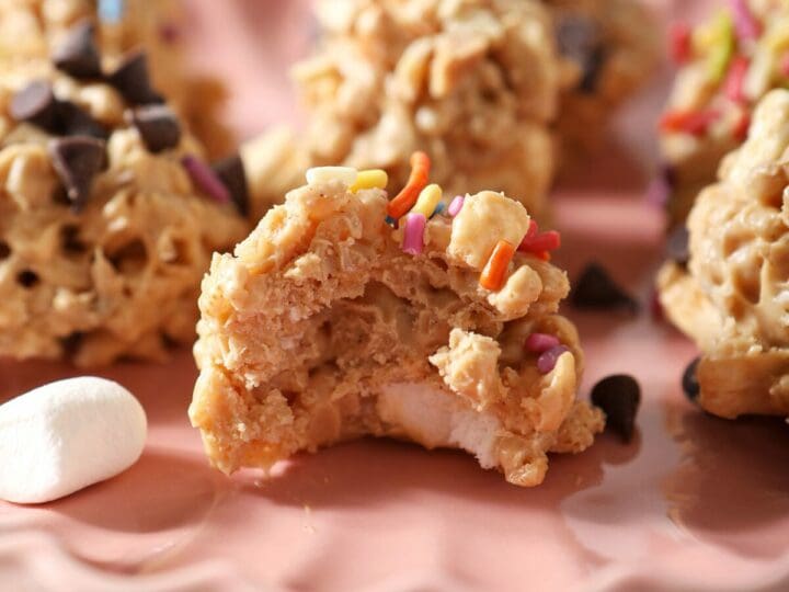 Close up of a bitten-into Avalanche Cookie topped with sprinkles on a pink plate