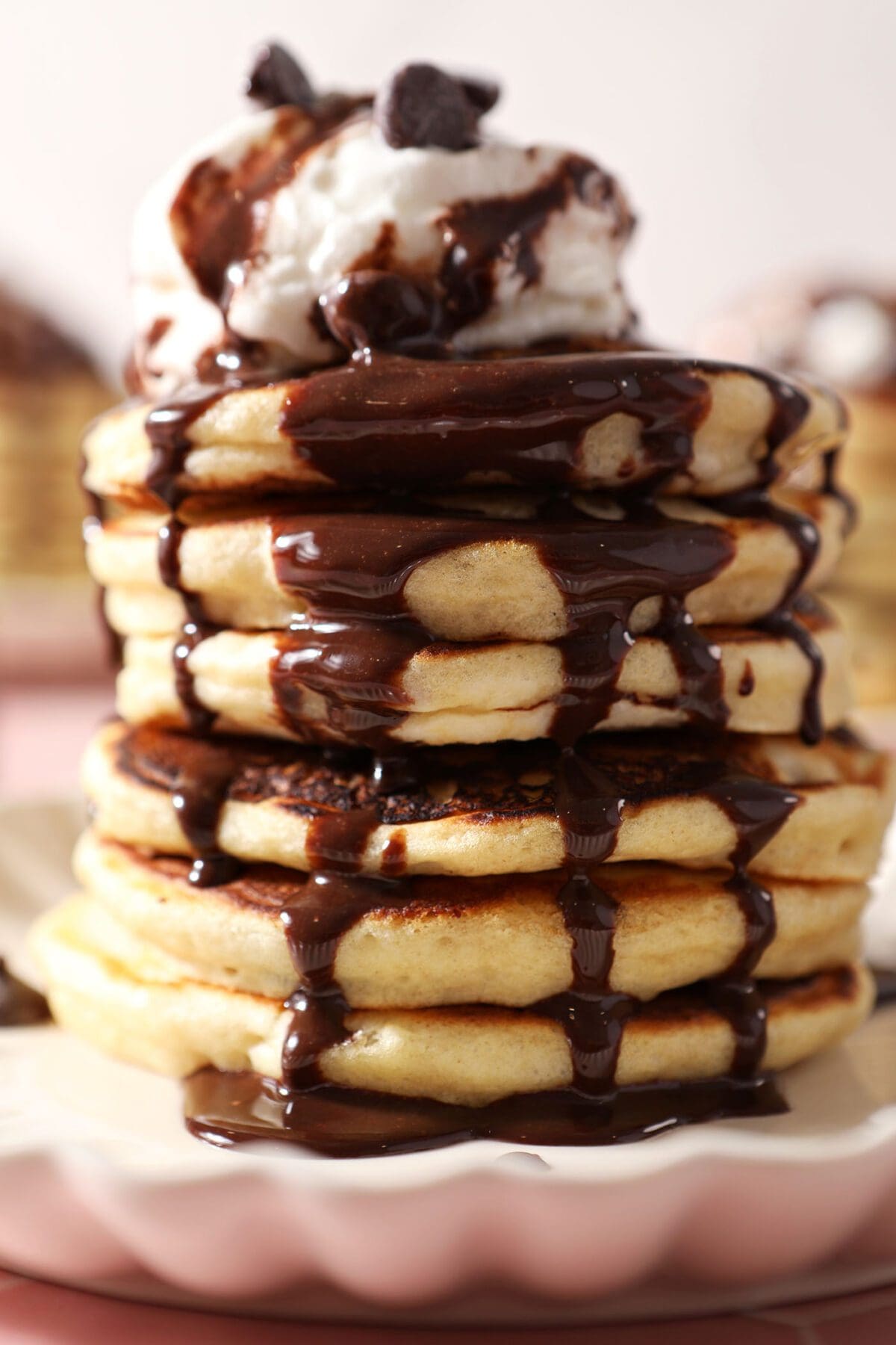 Close up of chocolate sauce drizzling down a tall stack of Chocolate Chip Pancakes