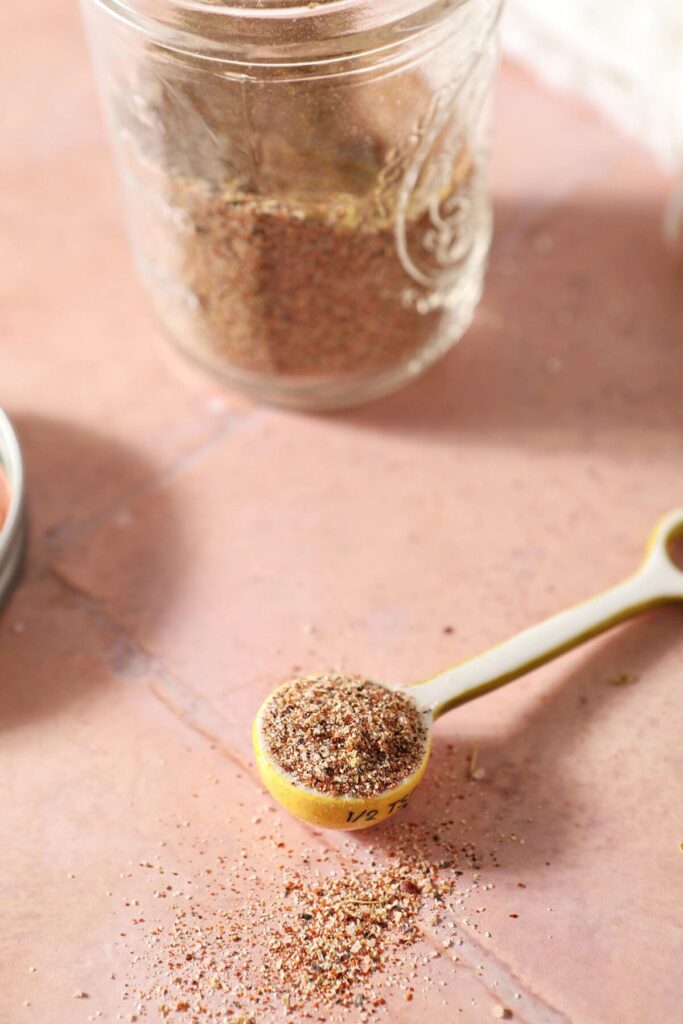 A teaspoon of spices next to a jar