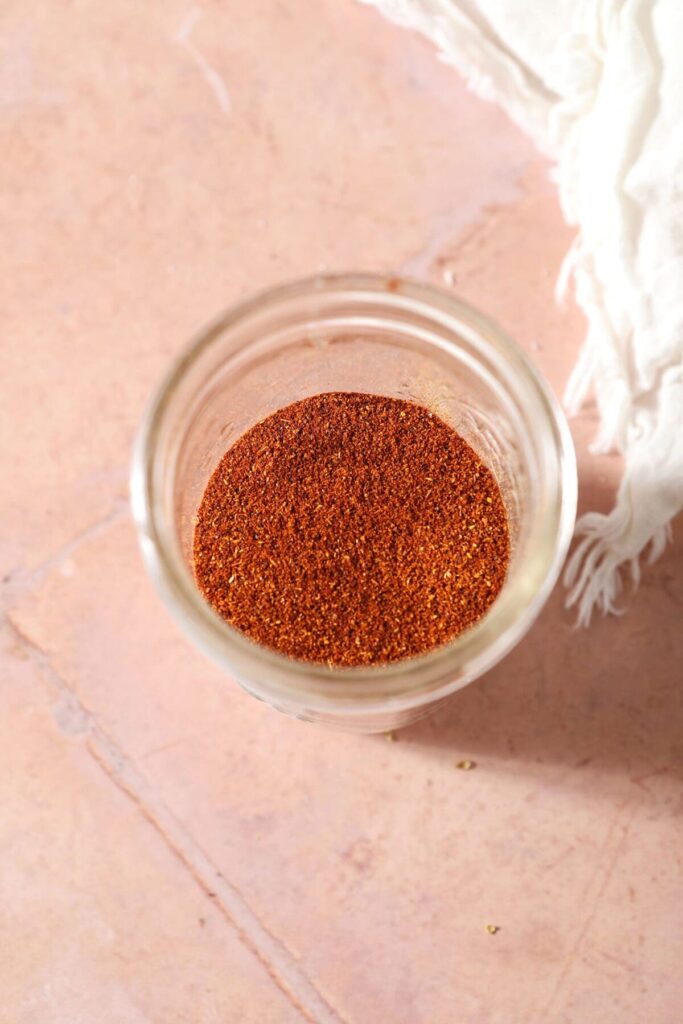 Red spices in a jar on tile