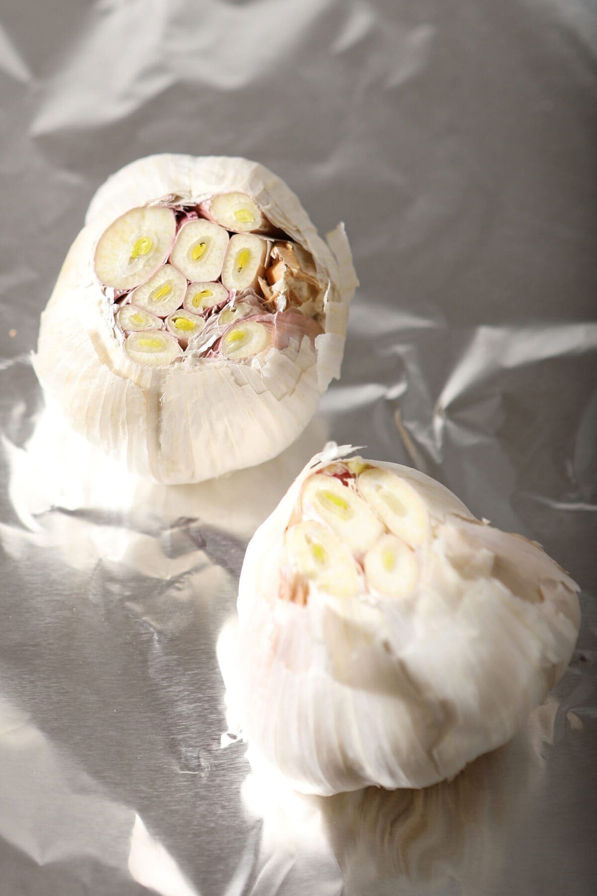 Trimmed garlic heads on foil before roasting