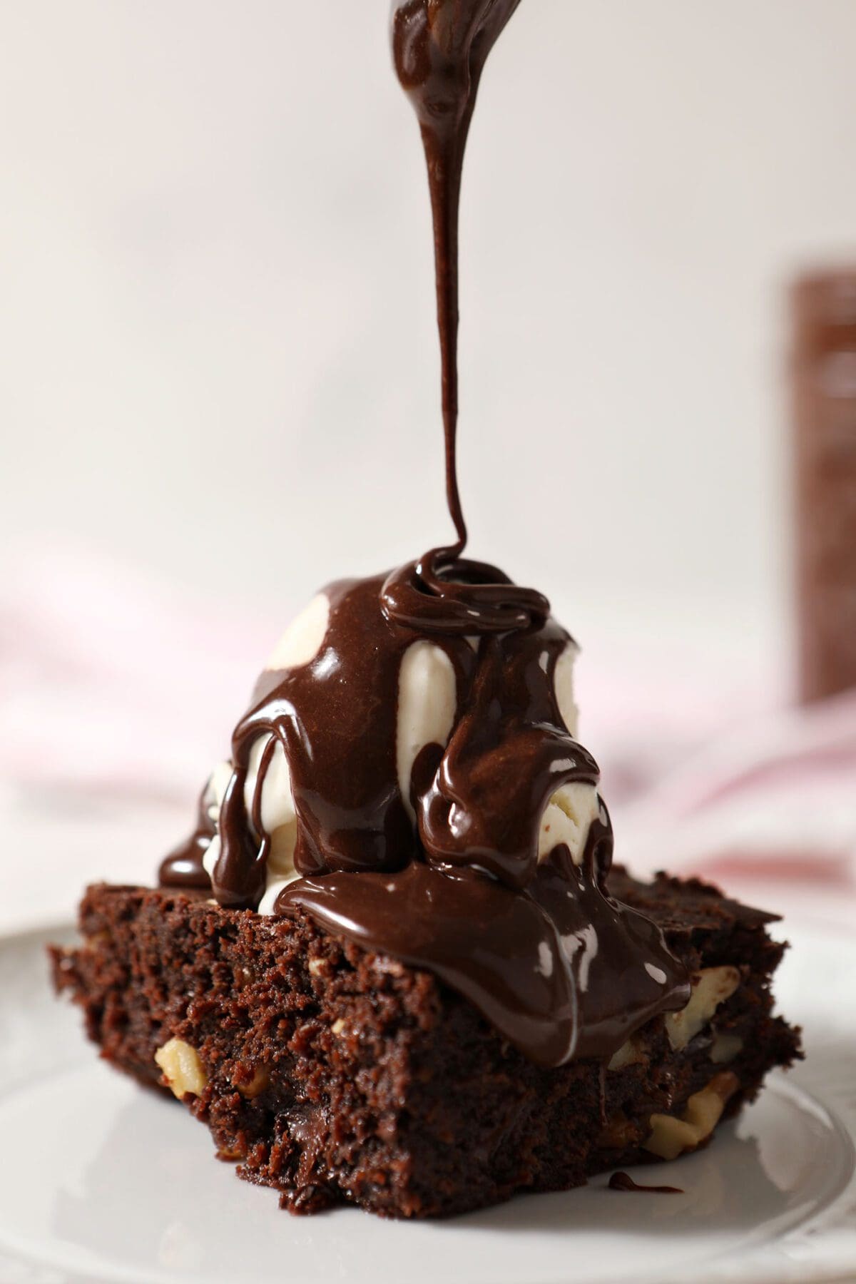 Hot fudge sauce drizzles on top of a brownie a la mode